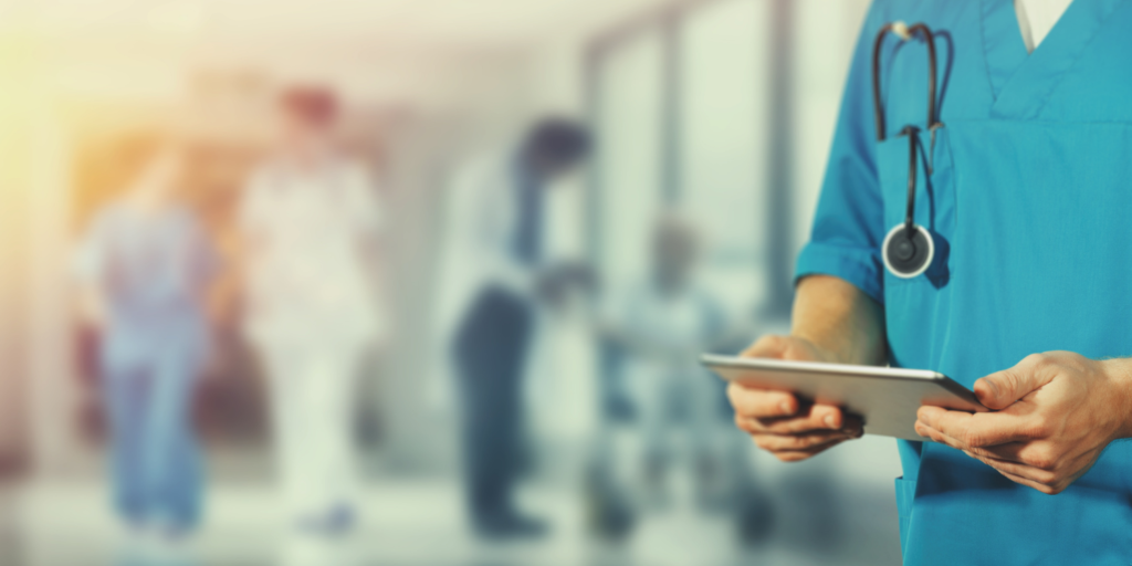 The torso of a doctor looking at their chart, with a stethoscope in top pocket